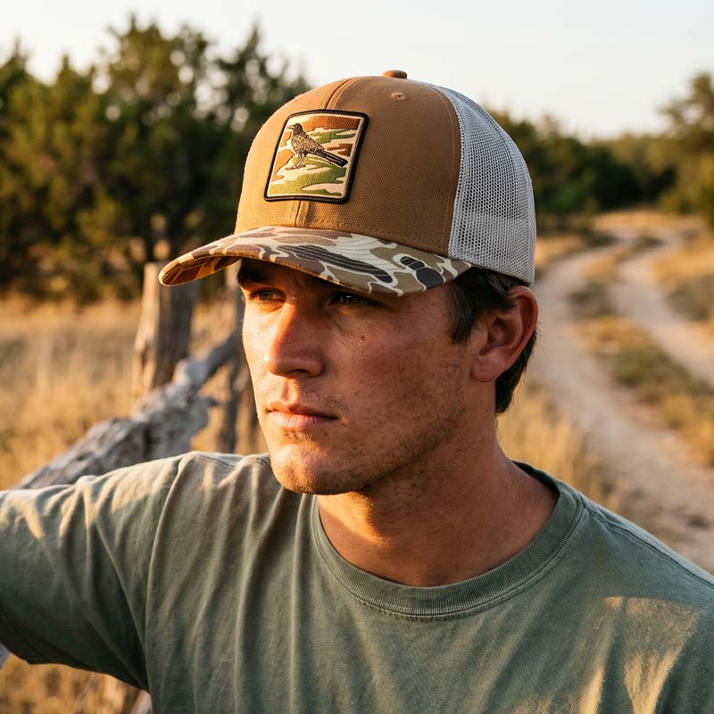 Man standing on the side of a road wearing City Camo Grackle Hat from Lost Draw Provisions