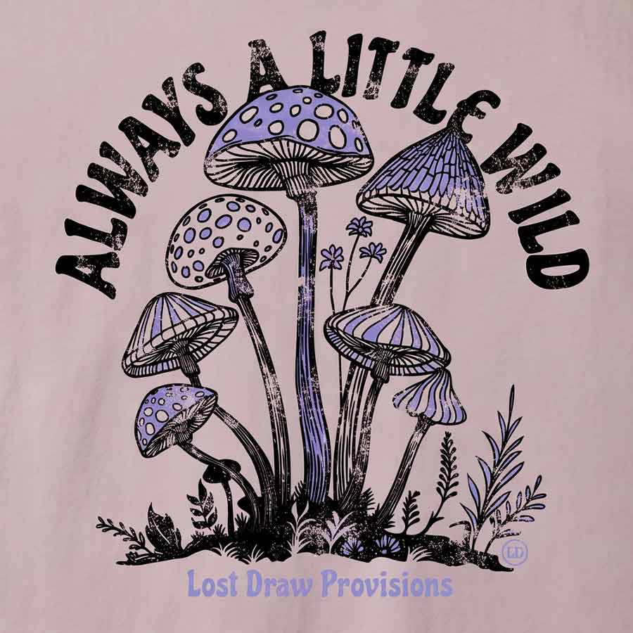 A close-up of a graphic print on a light pink fabric, featuring purple and black illustrated mushrooms with the text 'ALWAYS A LITTLE WILD' arched above and 'Lost Draw Provisions' below.
