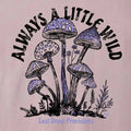 A close-up of a graphic print on a light pink fabric, featuring purple and black illustrated mushrooms with the text 'ALWAYS A LITTLE WILD' arched above and 'Lost Draw Provisions' below.