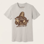 Catch of the Day Walleye Tee in BELLA+CANVAS Dust, featuring a vintage Bigfoot holding a walleye fish on the front.

