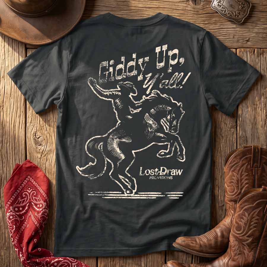 Dark Grey Giddy Up, Y'all Jersey Tee displayed with Western accessories, featuring the distressed cowboy and bucking horse back graphic.