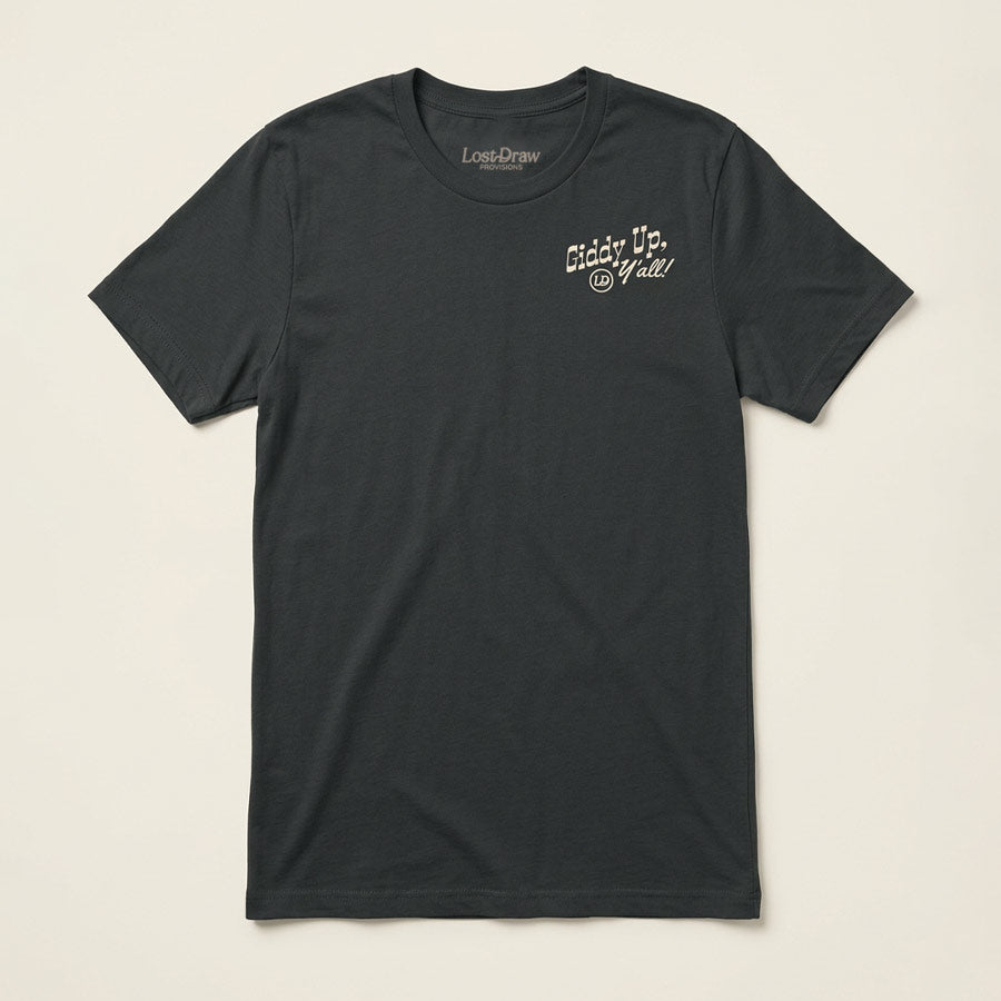 Front of the Giddy Up, Y'all Jersey Tee in Dark Grey with a small distressed cream-colored chest graphic.