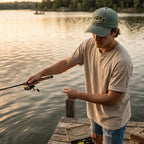 Man fishing on a dock by a lake during sunset