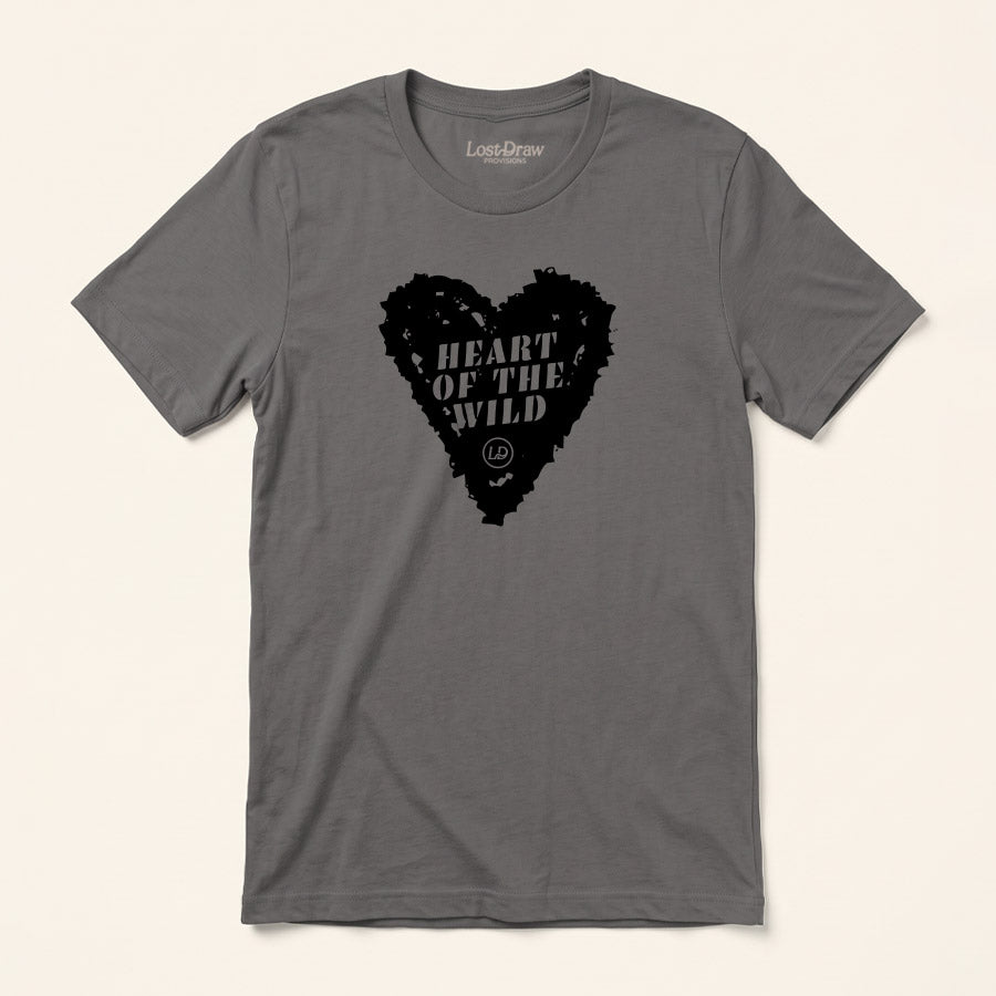 A dark gray crewneck t-shirt by LastDraw, featuring a black heart-shaped graphic on the chest with the text 'HEART OF THE WILD' and a small bear logo. The t-shirt is displayed flat against a light beige background.
