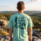 Person wearing a 'Lost Draw Provisions' t-shirt with a scenic view in the background