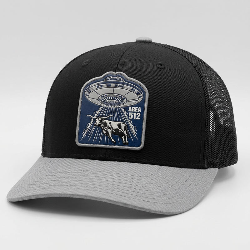 Black and gray cap with a UFO and cow patch on a light gray background
