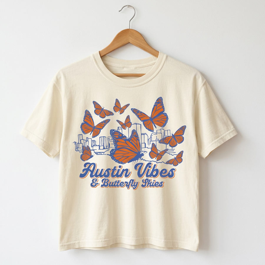 Butterfly Skies women’s boxy t-shirt with monarch butterflies and Austin skyline tee on a hanger against a white background