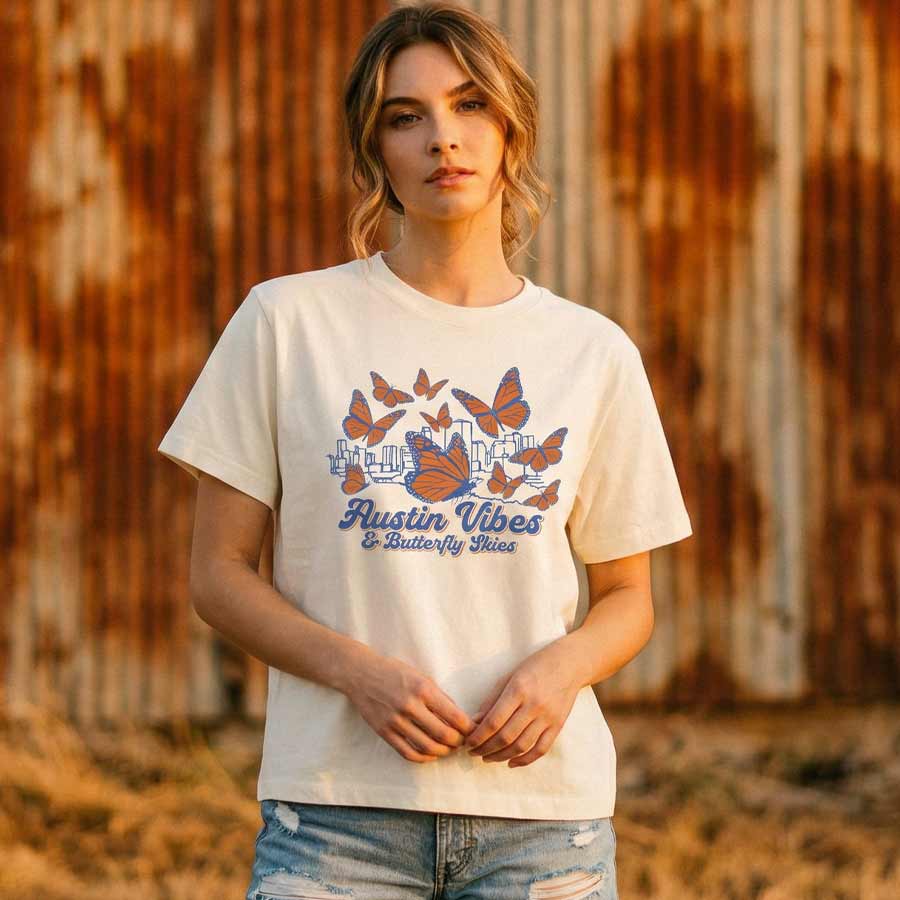 Woman  wearing a wearing a relaxed fit butterfly graphic tee against a rusty metal wall.