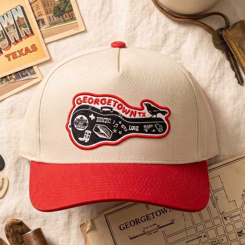 Cap with Georgetown, TX patch on a textured surface with vintage books and maps.