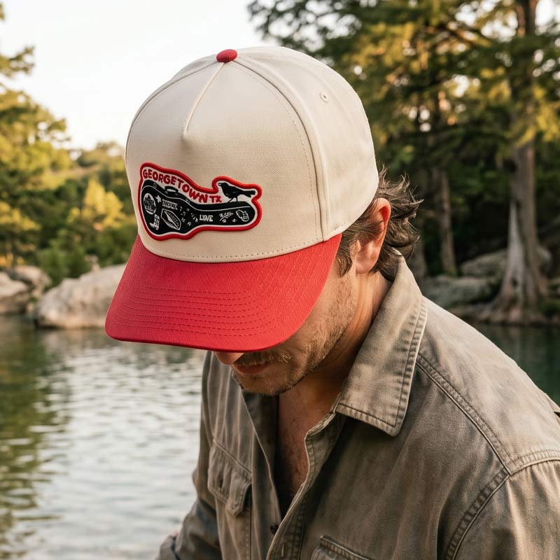 Man wearing a cap with a logo by a body of water