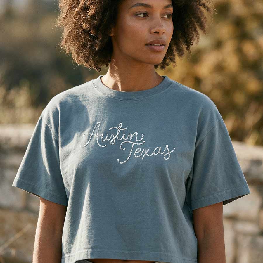 Lifestyle image of woman wearing relaxed fit Austin script tee