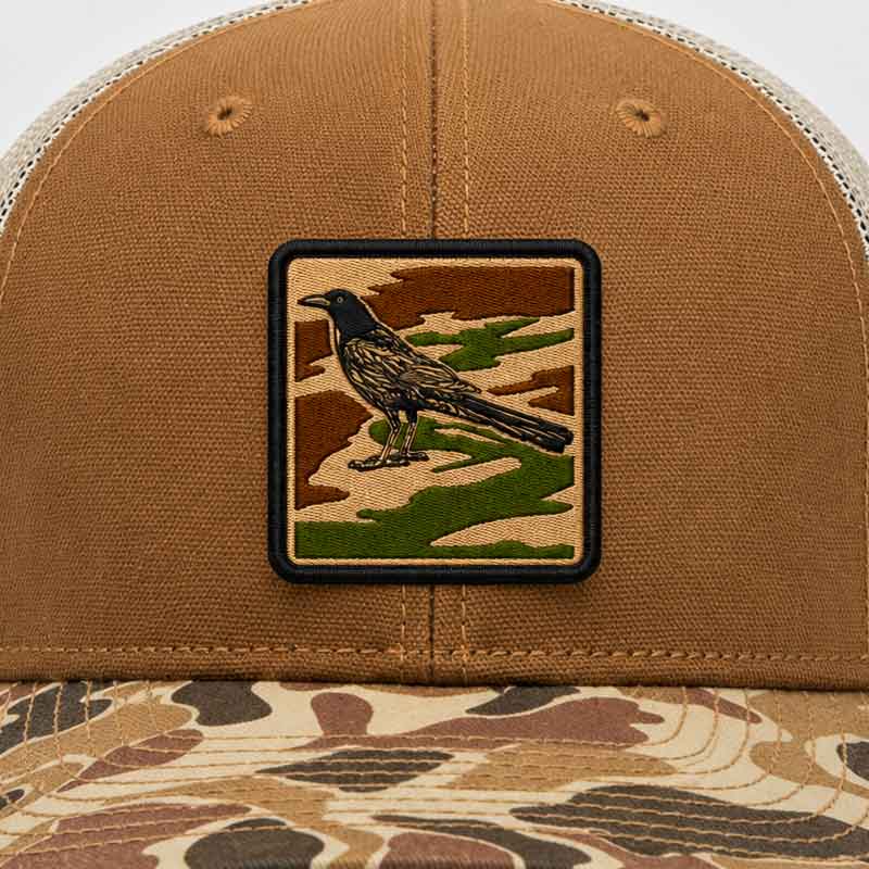 Brown cap with a bird patch on a camouflage background