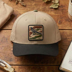 Beige and black cap with a bird patch on a wooden surface