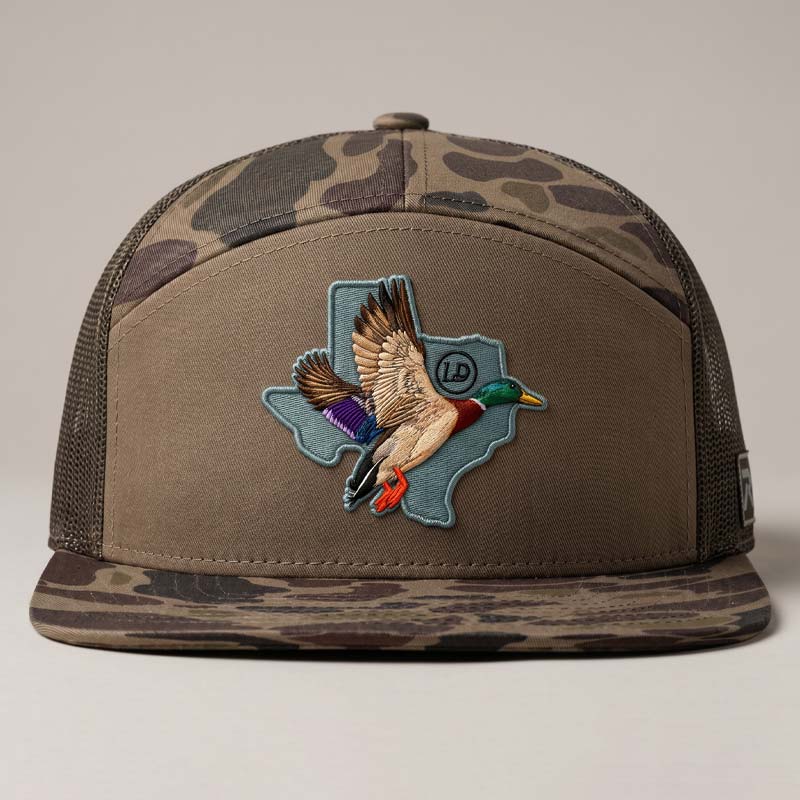 Camouflage cap with a duck and Texas shape patch on a neutral background