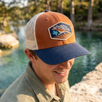 Man wearing a Georgetown cap by a body of water with trees in the background