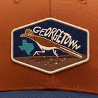 Cap with a Georgetown patch featuring a dinosaur and Texas map on an orange background