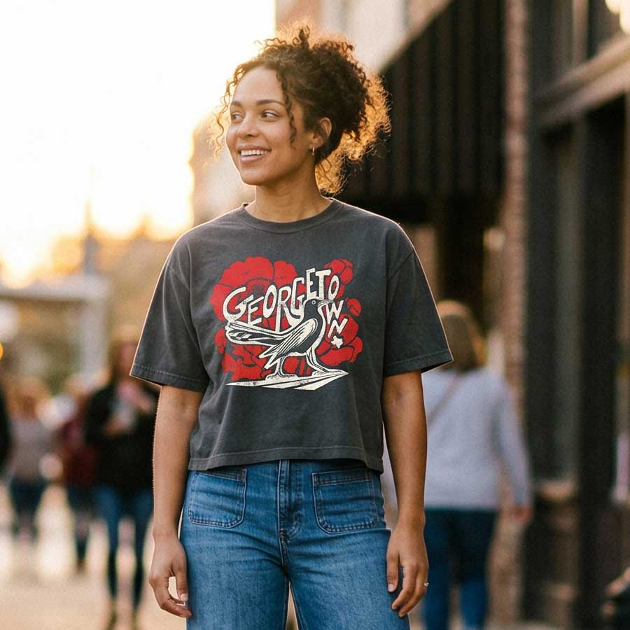 Woman wearing Grackle Strut Georgetown Texas women’s boxy t-shirt pepper garment-dyed graphic tee, standing on a street.