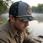 Man wearing a cap with a skull design by a body of water