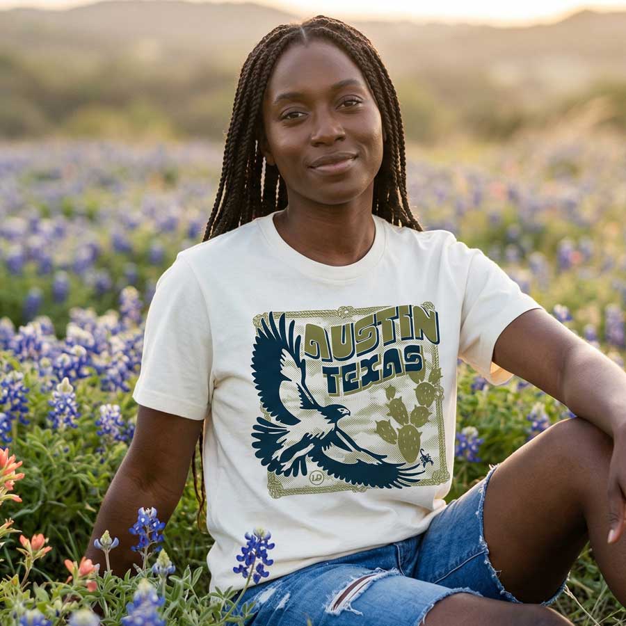 Women sitting in blue bonnets wearing heavyweight boxy tee with vintage hawk illustration in navy and olive tones 