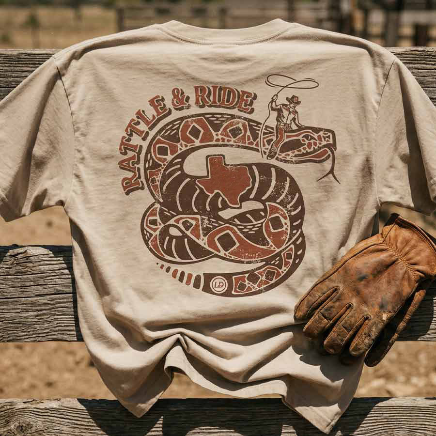 Rattle and Ride GTX Georgetown Texas graphic tee oversized tan heavyweight t-shirt Lost Draw Provisions on a wooden surface.