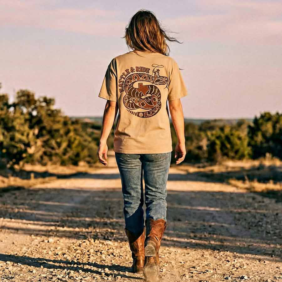 Woman walking on a dirt road wearing Rattle and Ride GTX Georgetown Texas graphic tee oversized tan heavyweight t-shirt Lost Draw Provisions 