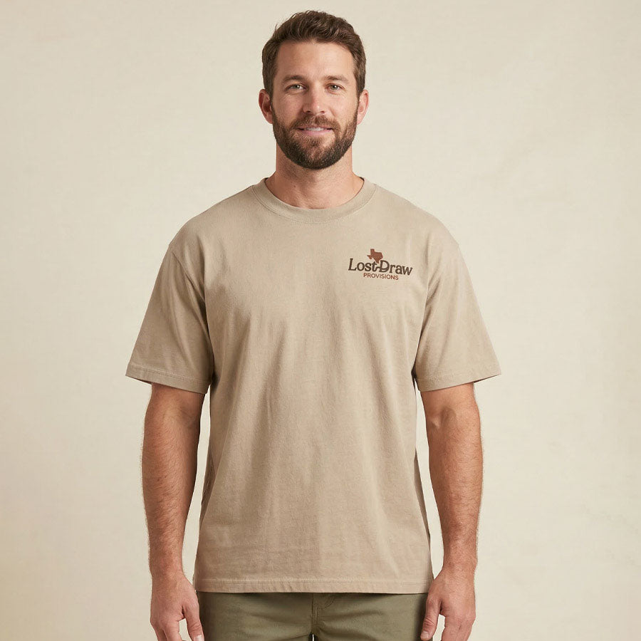 Man wearing a beige t-shirt with a logo on a beige background