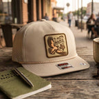 Beige cap with a logo on a wooden surface with a notebook and pen.