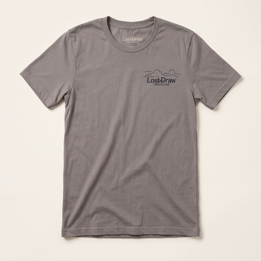 Front of the North of Ordinary Jersey Tee in Pebble Brown with a small Lost Draw Provisions landscape logo on the left chest.