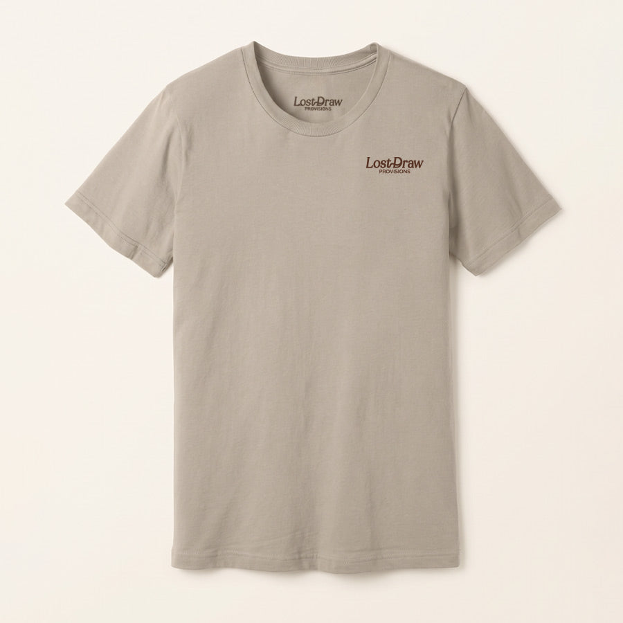 Front of the Rattle & Ride Jersey Tee in Dark Grey with a small rust-brown Lost Draw Provisions logo on the left chest.