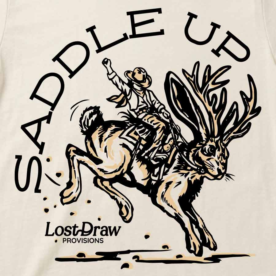 Close-up of Vintage White Saddle Up Jersey Tee featuring the cowboy riding a bucking jackalope.