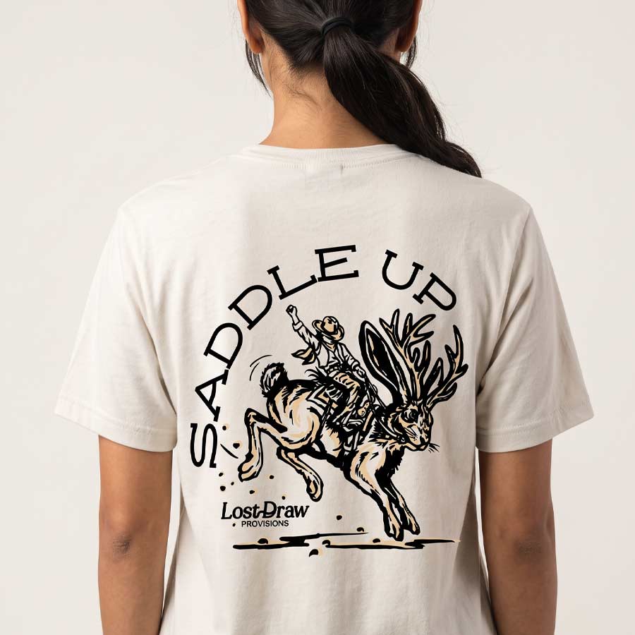 Back studio view of the Vintage White Saddle Up Jersey Tee featuring the cowboy riding a bucking jackalope.