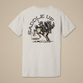 A white short-sleeve t-shirt with a black graphic print on the back, featuring the text 'SADDLE UP' and an illustration of a cowboy riding a bucking horse. The Lost Draw Brewing logo is printed below the graphic.