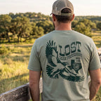 Back of the Lost Hawk Jersey Tee featuring distressed forest-green hawk illustrations, vintage Lost Draw Provisions lettering, and Texas artwork on a Thyme green shirt.