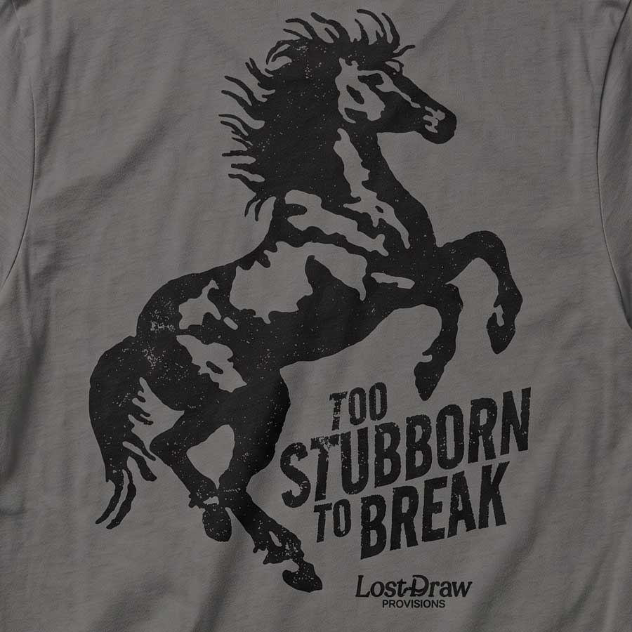 Close-up of the Too Stubborn Tee's distressed black rearing horse and Too Stubborn to Break artwork on Asphalt fabric.