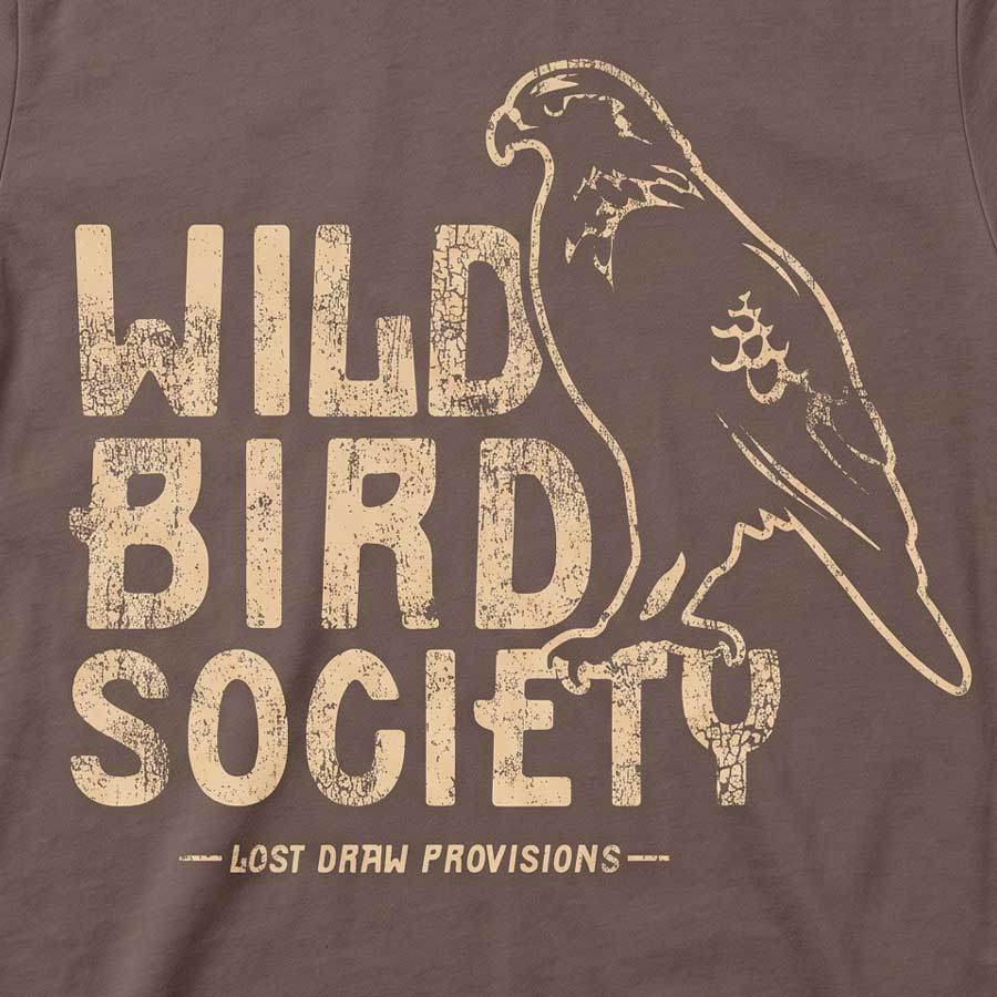 Close-up of the Wild Bird Society Tee's distressed cream bird illustration and lettering on Cocoa fabric.